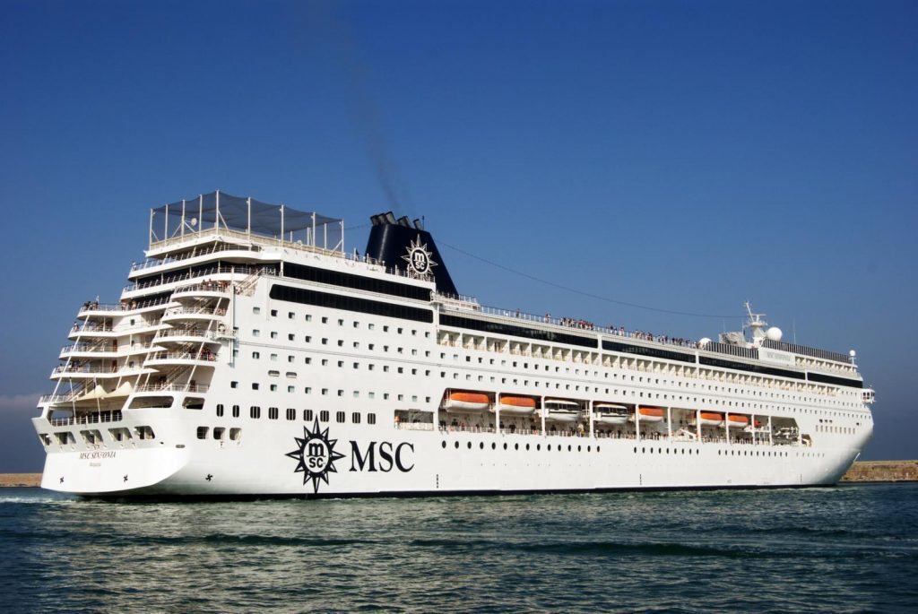 MSC Sinfonia cruise ship sailing in calm waters under clear blue skies, showing its white hull and multiple passenger decks