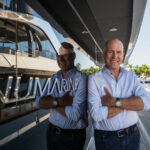 Patrik von Sydow standing on a Numarine yacht, smiling with arms crossed, reflected in the vessel’s glass panel with the Numarine logo visible