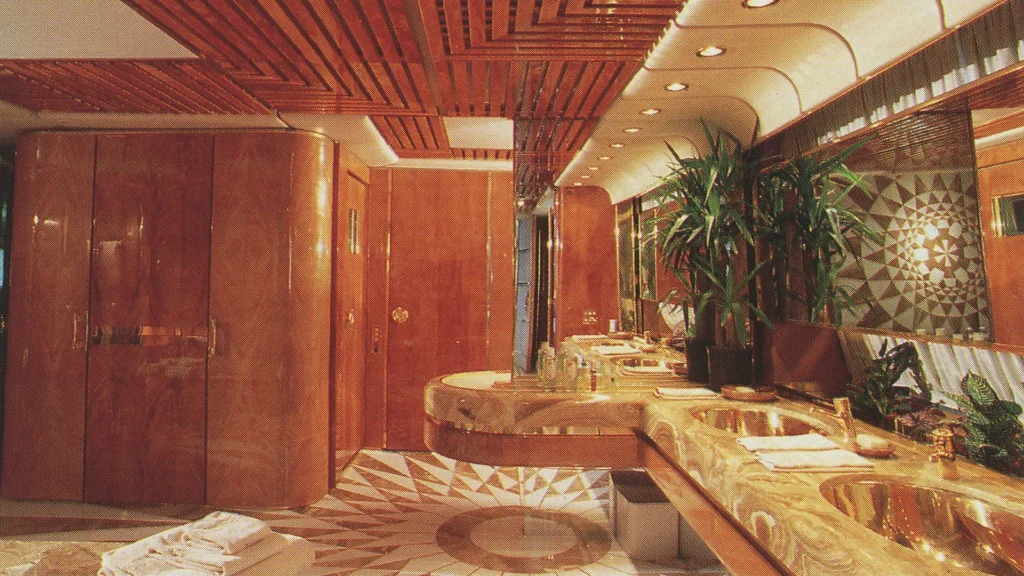 En-suite bathroom aboard Trump Princess with marble surfaces, gold-toned fixtures, and custom-built vanity